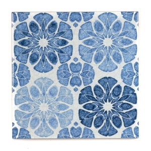 May include: A square ceramic tile with a blue and white floral pattern. The tile features a repeating design of stylised flowers with intricate details.