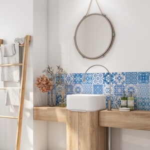 Pode incluir: Um lavatório de banheiro com uma pia de porcelana branca e um espelho redondo com um detalhe de corda. O lavatório é feito de madeira clara e tem um backsplash de azulejos azuis e brancos.