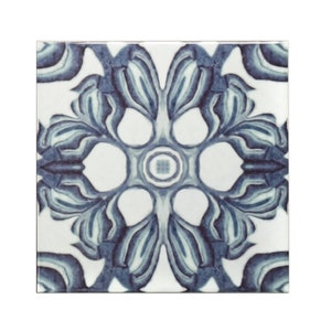 May include: A blue and white ceramic tile with a floral pattern. The tile has a symmetrical design with a central circle and four petals.