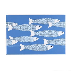 May include: A rectangular blue decorative tile featuring a pattern of stylized fish swimming across the surface. Each fish has a white tail and head, with a blue and white patterned body. The fish are arranged in a horizontal orientation.
