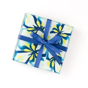 May include: Set of four blue and yellow floral coasters tied together with a blue ribbon.