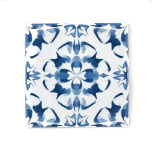 Könnte beinhalten: Eine quadratische Keramikfliese mit einem geometrischen Muster in Blau und Weiß. Das Muster ist ein sich wiederholendes Design aus stilisierten Blumen und Blättern.