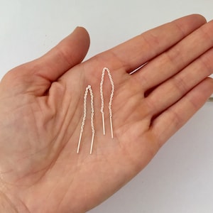 May include: A pair of silver chain earrings with a straight bar at the end of each chain.