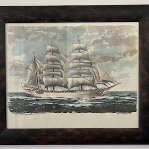 May include: A white ceramic mug with a black handle and the text "But First, Coffee" in a bold, black font. The mug is filled with a dark liquid, likely coffee, and sits on a light-colored surface.