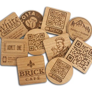 May include: A collection of wooden coasters with various designs and text. Some coasters feature QR codes, while others display logos for "White Realty Co.", "Costa Coffee", "Brick Cafe", and "Tasty Grill". One coaster is for a wedding, and another is an "Admit One" ticket.