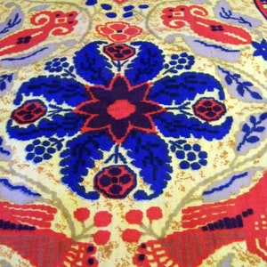 May include: A vintage fabric with a repeating pattern of stylized flowers, birds, and geometric shapes. The fabric is primarily yellow with red, blue, and purple accents.