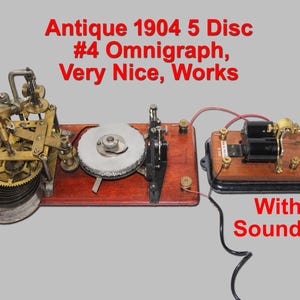 May include: An antique 1904 5 Disc #4 Omnigraph telegraph transmitter with a sounder. The device features brass gears, a circular disc, and a wooden base, connected by red and black wires. Text reads: Antique 1904 5 Disc #4 Omnigraph, Very Nice, Works With Sounder.
