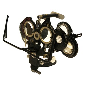 May include: A vintage black metal eye chart with multiple dials and lenses. The chart is used by an optometrist to test a patient's vision.