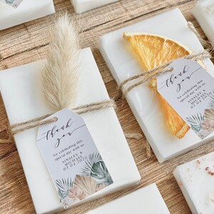 May include: White favour boxes with a thank you tag, a dried orange slice, and a sprig of pampas grass. The tag says "thank you for celebrating this special day with us Ainsley & Michael 03.04.2020".