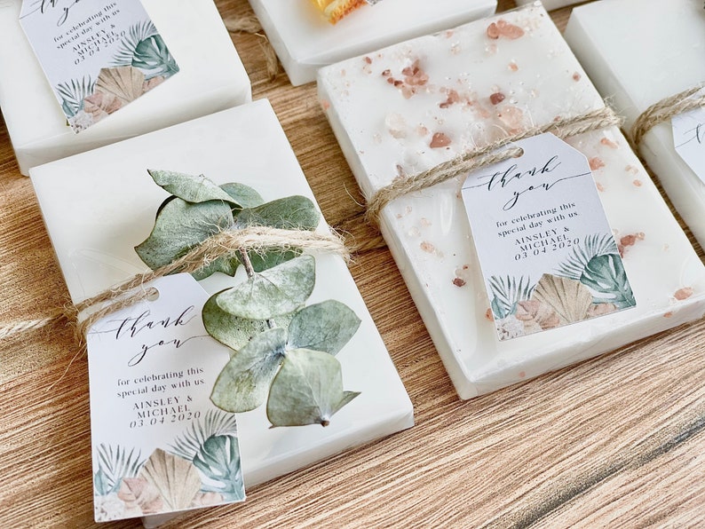 May include: White soap bars with a natural, earthy theme. Each bar is wrapped with twine and decorated with dried eucalyptus leaves and a small tag that says "Thank you for celebrating this special day with us Ainsley & Michael 03.04.2020".