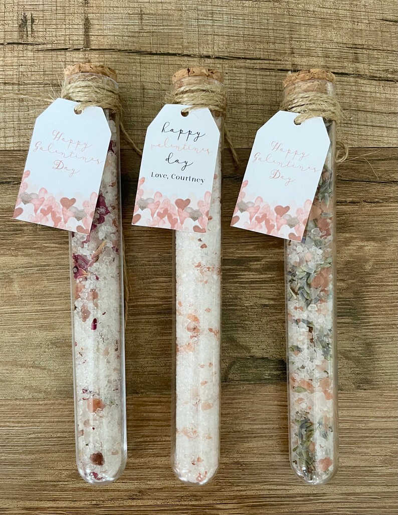 May include: Three glass test tubes with cork tops and twine tied around the tops. Each tube contains bath salts and has a tag attached. The tags are white with pink hearts and the text "Happy Valentine's Day" and "Happy Valentine's Day, Love, Courtney".