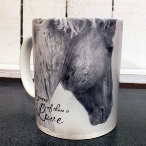 May include: White ceramic mug with a black and white photo of a horse's head. The text "The greatest of these is Love" is printed on the mug.