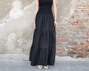 May include: A black sleeveless top with a black tiered maxi skirt. The skirt has multiple layers of fabric.