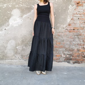 May include: A black sleeveless top with a black tiered maxi skirt. The skirt has multiple layers of fabric.