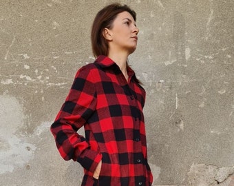 May include: A long-sleeved, red and black plaid shirt dress with a button-down front and side pockets. The dress is paired with black leggings and cream-colored boots.