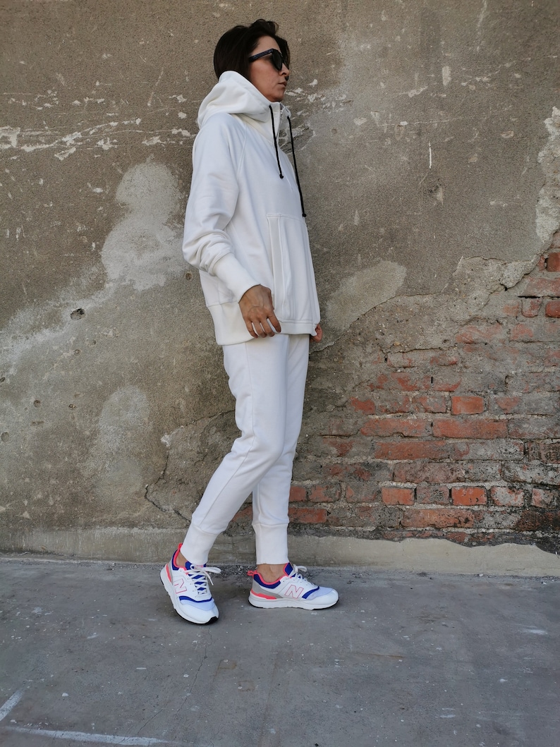 May include: A white hooded sweatshirt and matching sweatpants with a pair of white sneakers with pink and blue accents.