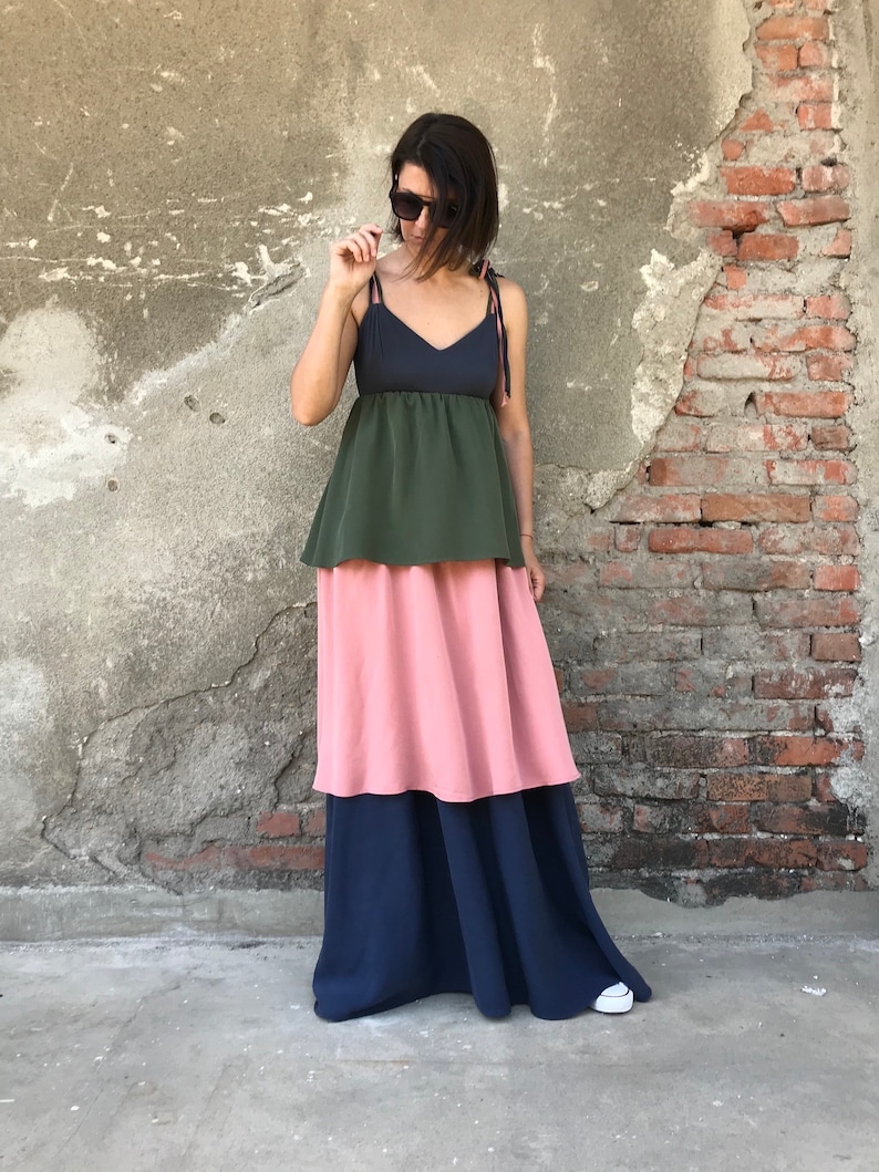 May include: A tiered maxi dress with a dark blue, green, and pink color scheme. The dress has a fitted bodice and a flowing skirt.