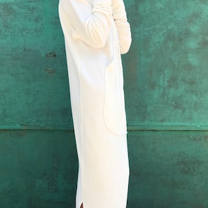 Pu&ograve; includere: Un abito bianco con cappuccio in felpa con uno spacco laterale. L'abito &egrave; realizzato in un tessuto morbido e confortevole e ha una vestibilit&agrave; rilassata.