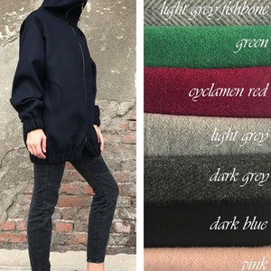 May include: A navy blue mock neck jacket with a zipper closure. The jacket is shown with black jeans and pink sneakers. The image also shows swatches of fabric in various colors and patterns, including dark grey fishbone, light grey fishbone, green, cyclamen red, light grey, dark grey, dark blue, pink, and plaid.