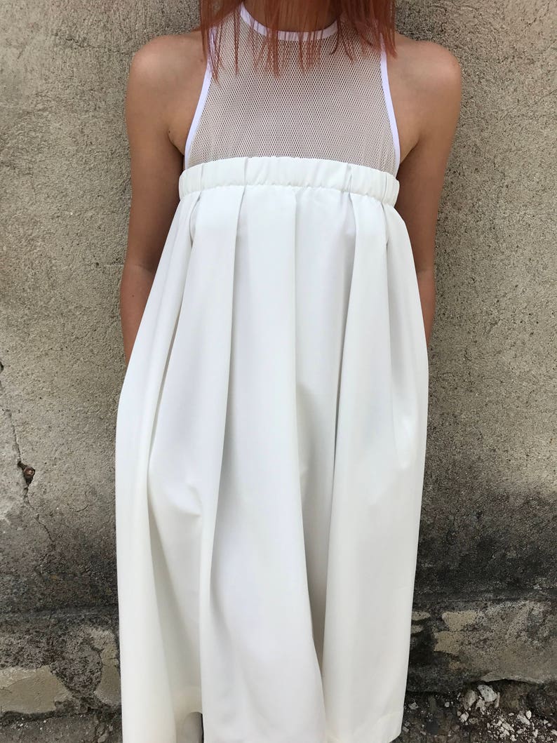 May include: A white sleeveless dress with a mesh panel at the top and a pleated skirt.