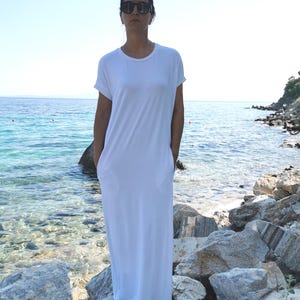 May include: A white maxi dress with short sleeves and pockets. The dress is made of a soft, comfortable fabric and is perfect for a casual summer look.