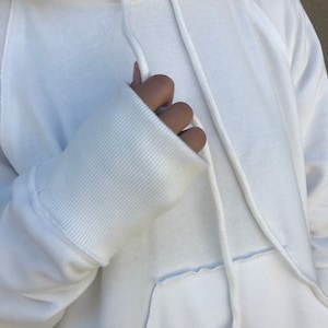 Pu&ograve; includere: Felpa bianca oversize con cappuccio con coulisse e polsino a costine sulla manica.