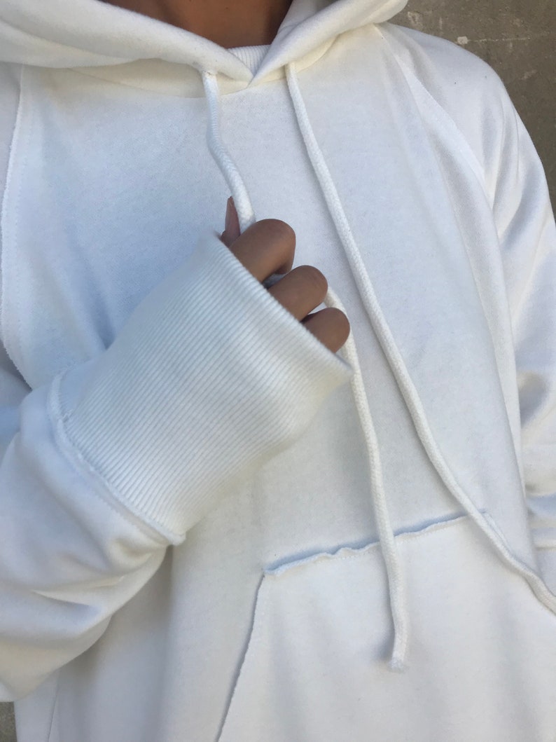 Pu&ograve; includere: Felpa bianca oversize con cappuccio con coulisse e polsino a costine sulla manica.