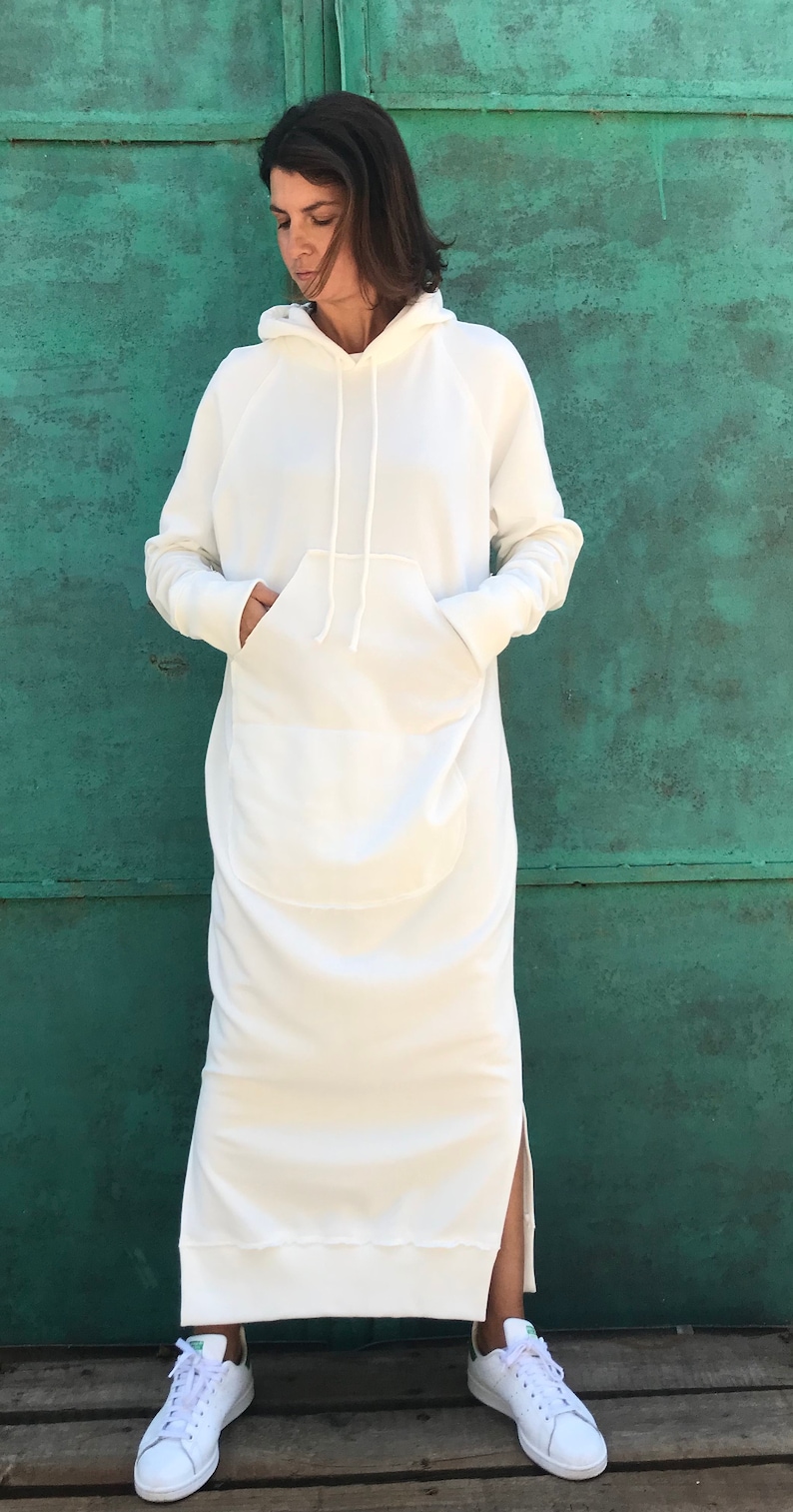 Pu&ograve; includere: Un vestito bianco con cappuccio in felpa, con una grande tasca anteriore e spacchi laterali. Il vestito &egrave; realizzato in un tessuto morbido e confortevole e ha una vestibilit&agrave; rilassata.