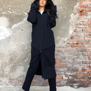 May include: A long black hooded jacket with a zipper down the front. The jacket has a long, flowing design and is made of a soft, comfortable fabric.