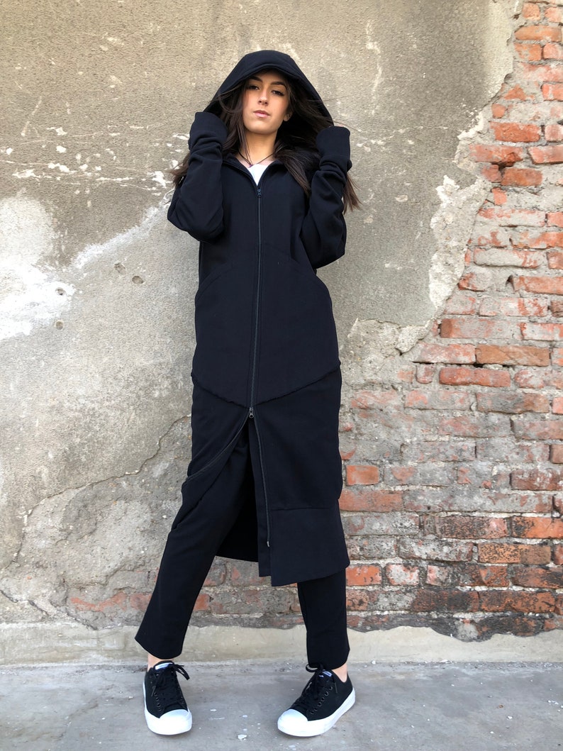 May include: A long black hooded jacket with a zipper down the front. The jacket has a long, flowing design and is made of a soft, comfortable fabric.