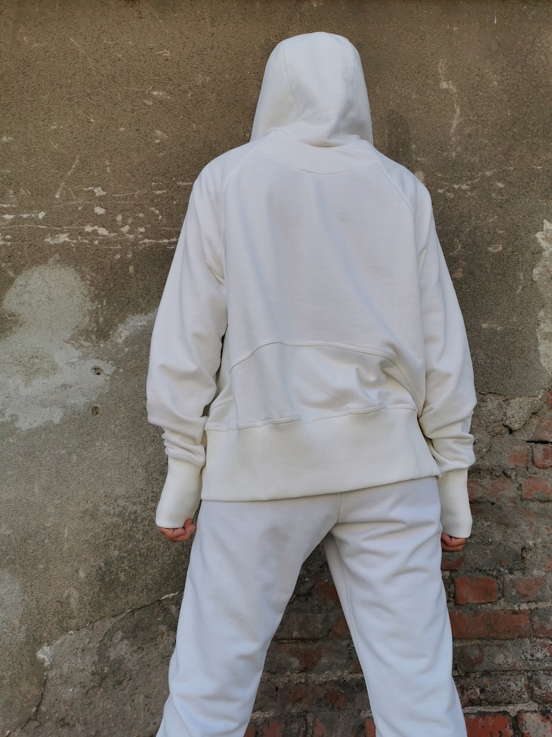 May include: A white hooded sweatshirt with a drawstring hood and long sleeves. The sweatshirt is paired with matching white sweatpants.