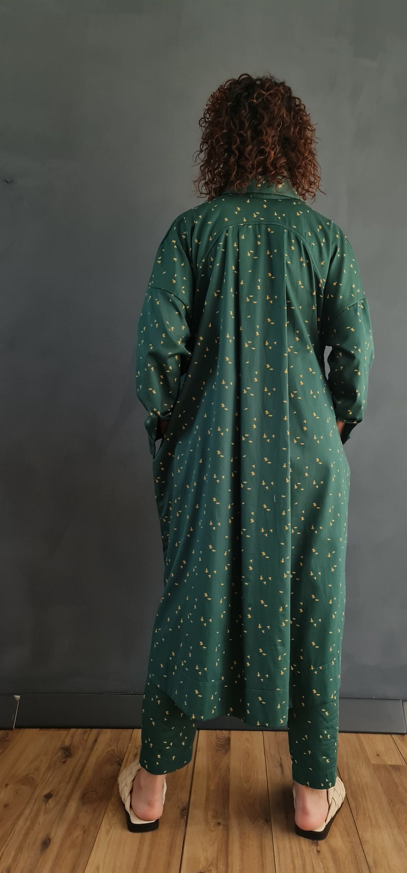 May include: A green and yellow patterned shirt and pants set. The shirt has a long sleeve and a collared neckline. The pants are long and have a straight leg.