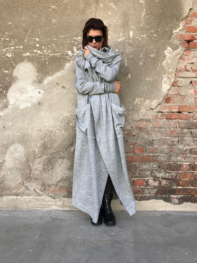 May include: A long, gray, hooded cardigan with a draped cowl neck and large pockets. The cardigan is made of a soft, comfortable fabric and has a relaxed fit.