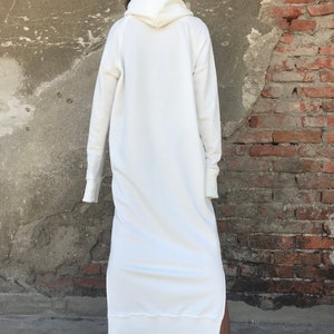 Pu&ograve; includere: Un vestito bianco con cappuccio a felpa con maniche lunghe e uno spacco laterale. Il vestito &egrave; realizzato in un tessuto morbido e confortevole e ha una vestibilit&agrave; rilassata.