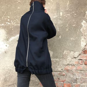 May include: A navy blue mock neck sweatshirt with a long zipper down the back. The sweatshirt has a gathered elastic waistband.