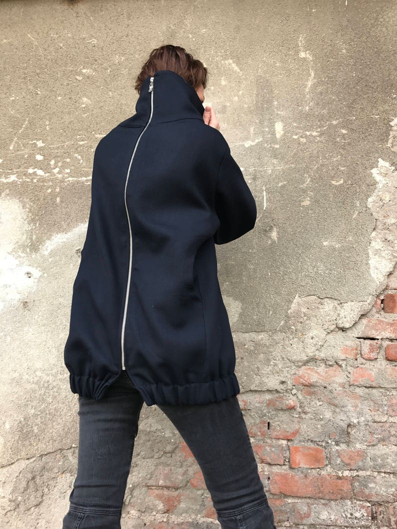 May include: A navy blue mock neck sweatshirt with a long zipper down the back. The sweatshirt has a gathered elastic waistband.