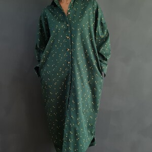 May include: A long-sleeved green shirt with a small yellow floral pattern. The shirt has a button-down front and is worn with matching pants.