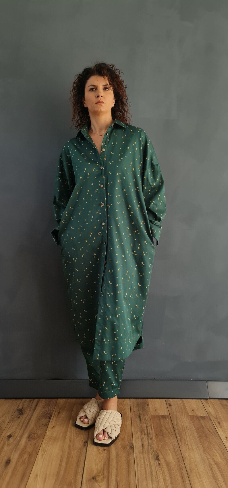 May include: A long-sleeved green shirt with a small yellow floral pattern. The shirt has a button-down front and is worn with matching pants.