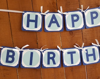 May include: A blue and white banner with the words "Happy Birthday" in white letters on a blue background. The banner is strung on a white ribbon and is hanging on a wooden wall.