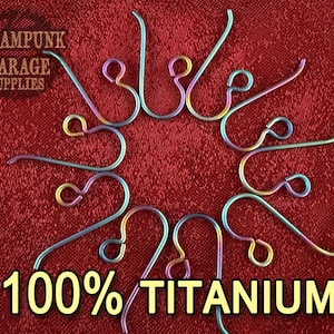 May include: A collection of iridescent titanium earring hooks arranged on a red textured surface. The hooks are in various shades of blue, purple, and gold. The text "Steampunk Garage Supplies" and "100% TITANIUM!" are visible.