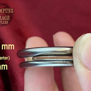 May include: Two metal rings, one 4.5 mm and one 3 mm in diameter, are shown next to a US quarter for size comparison. The rings are silver in color and have a smooth, polished finish.