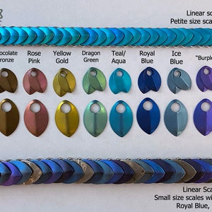 May include: Two rows of metal scales in various colors, including raw silver, chocolate bronze, rose pink, yellow gold, dragon green, teal/aqua, royal blue, ice blue, "burple", and violet purple. The scales are arranged in a linear pattern. The top row is labeled "Petite size scales; all Teal/Aqua". The bottom row is labeled "Small size scales with a mix of "Burple", Royal Blue, and Ice Blue."