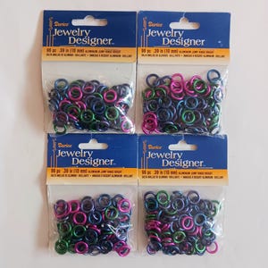 May include: Four packages of Darico Jewelry Designer jump rings. Each package contains 96 pieces of .39 inch (10 mm) aluminum jump rings in various colors, including blue, pink, and green. The packaging has a blue header with product information.