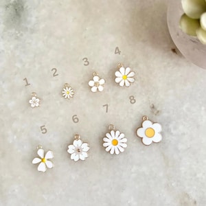 May include: Ten white and yellow daisy flower charms with gold accents. The charms are numbered 1 through 8.