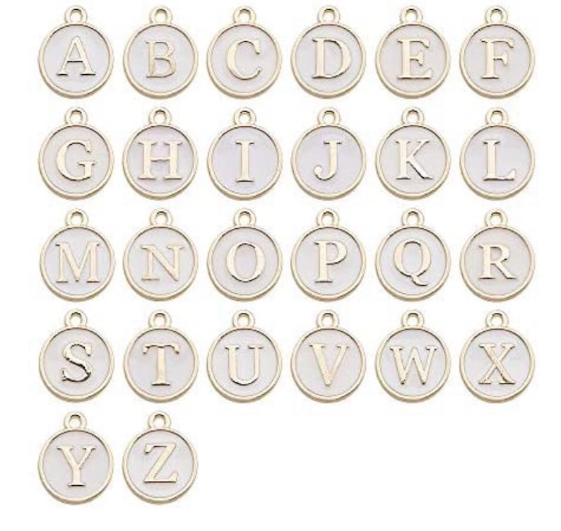 May include: A set of 26 gold-colored metal alphabet letter charms. Each charm is a circle with a white background and a gold letter in the center. The letters are in alphabetical order from A to Z.
