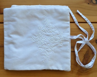 Puede incluir: Bolsa de algodón blanco con un diseño floral bordado en blanco y un cierre de cordón blanco.