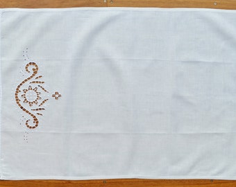 May include: White cotton tea towel with a delicate lace border and a decorative embroidered design featuring a floral motif and a cross.
