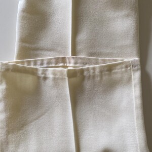 May include: A pair of white trousers folded in half, showing the seam down the centre of the front.