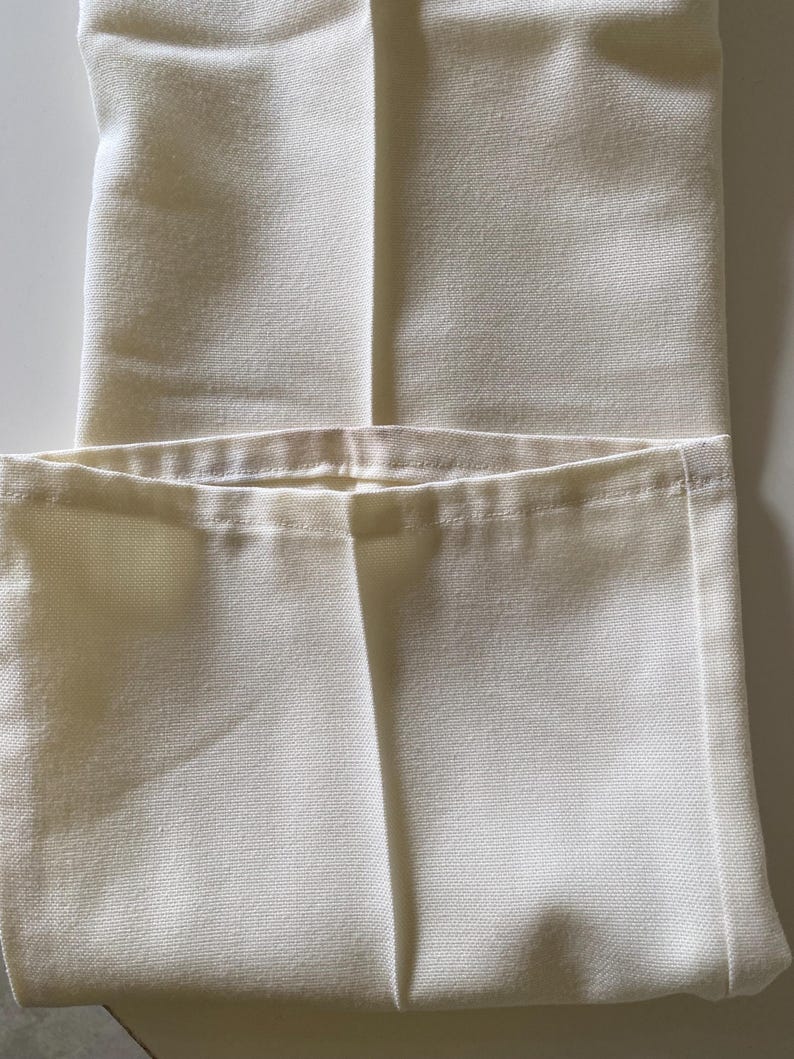 May include: A pair of white trousers folded in half, showing the seam down the centre of the front.