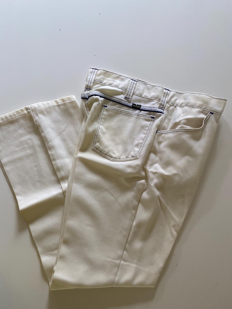 May include: A pair of off-white jeans with white stitching and a blue label on the back pocket.